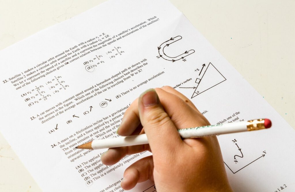 Eine Person füllt eine Seite einer Prüfung aus, bei der es um mathematische Formeln und Gleichungen geht.