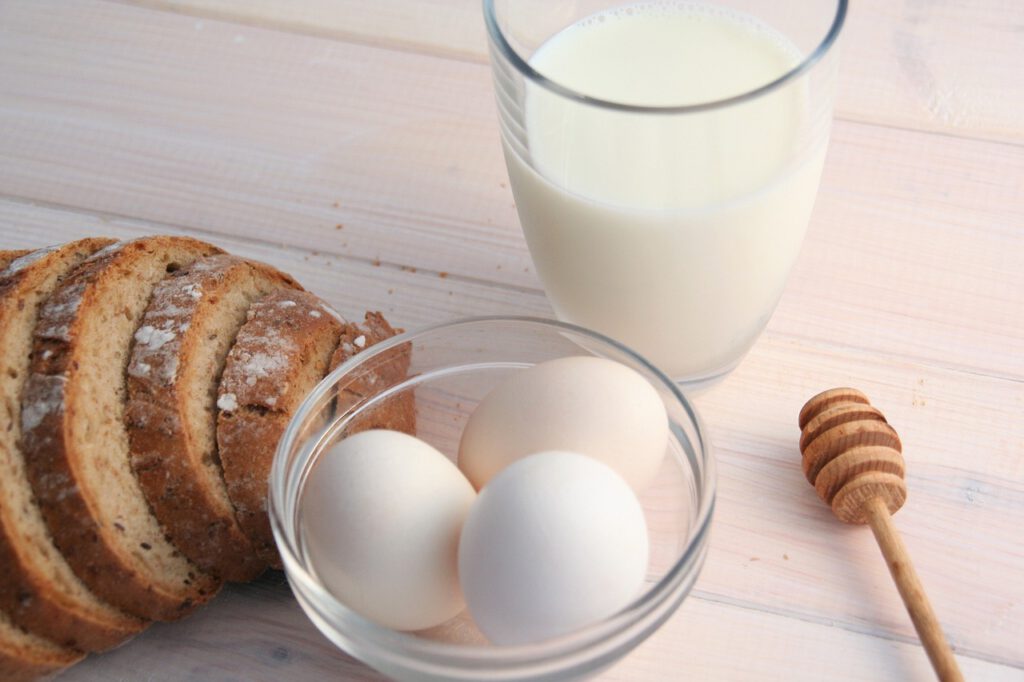 Ein Holztisch mit frischem Brot, Eiern und Milch.