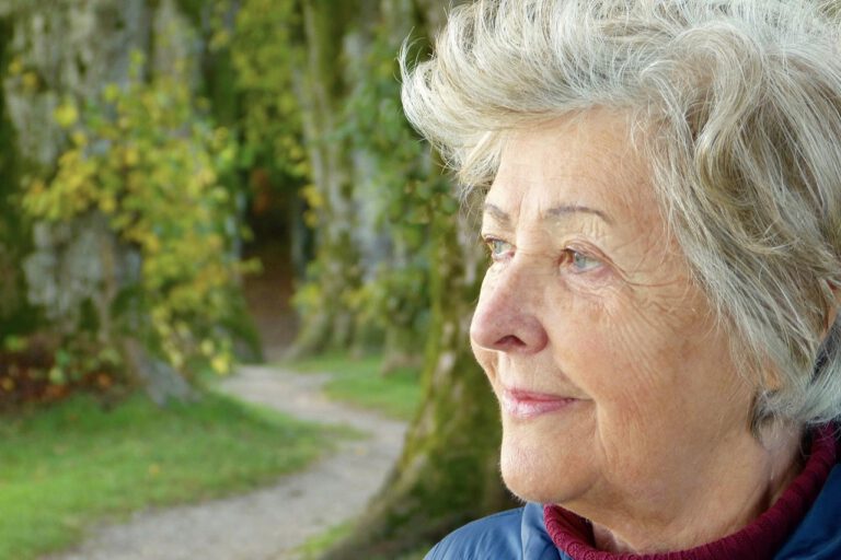 Eine ältere Dame schaut in die Ferne. Ihr Gesicht zeugt von Lebenserfahrung.
