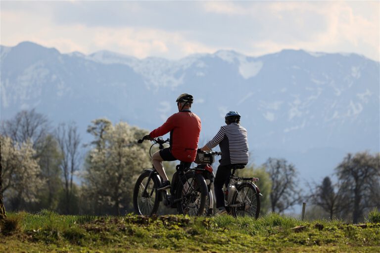 Ein älteres Ehepaar macht eine Fahrradtour in einer bergigen Landschaft.