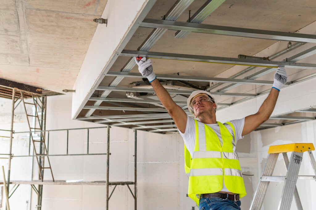 Ein Handwerker in Schutzausrüstung bei seiner Arbeit auf der Leiter.