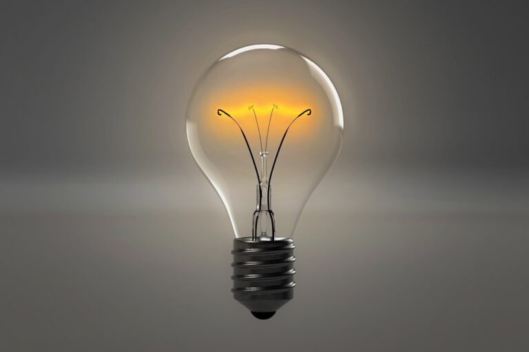 Eine echte, hell leuchtende Glühbirne vor einem schlichten, grauen Hintergrund.